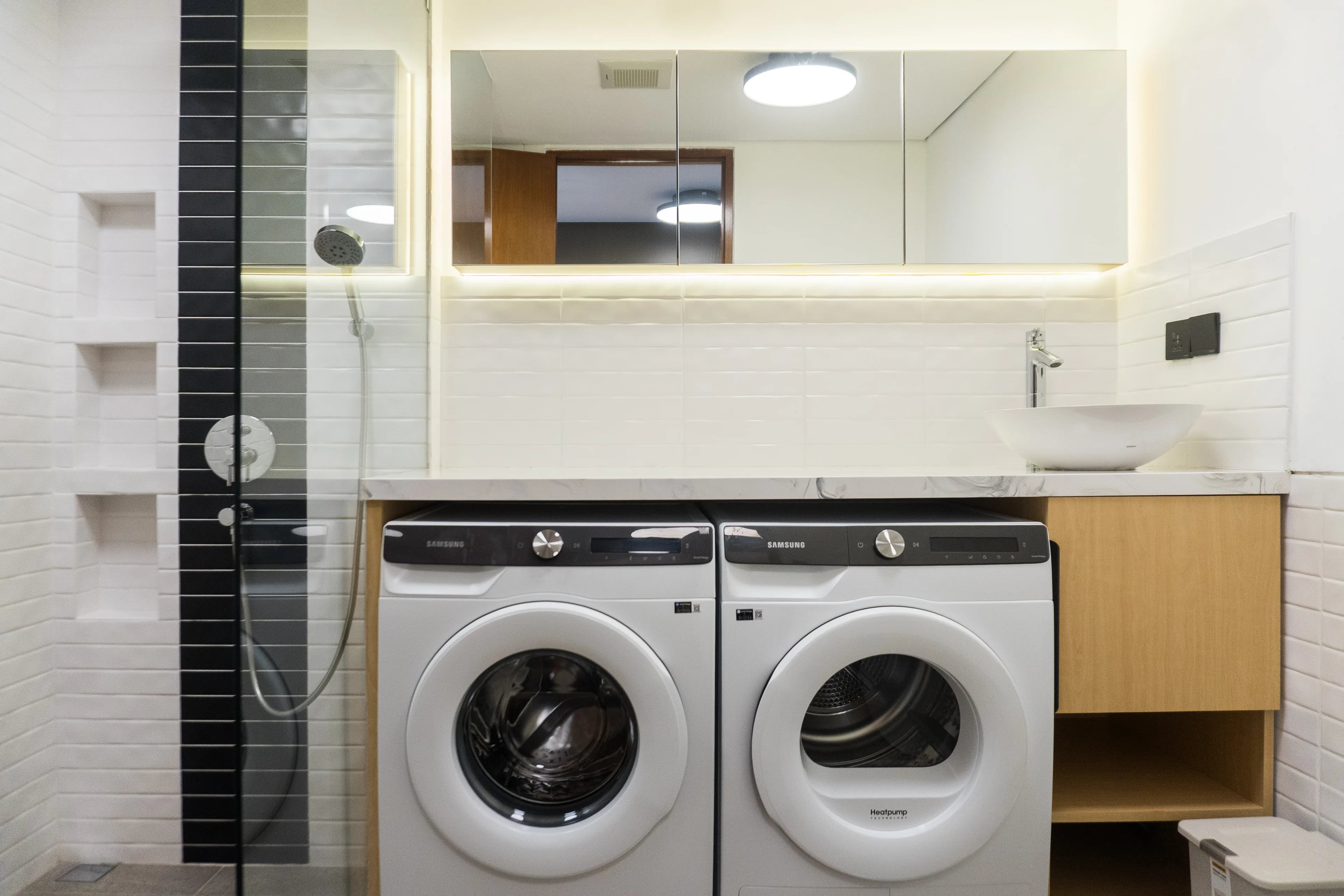 Bathroom in a renovated de Lagoon residence, with a walk-in shower and a washer and dryer