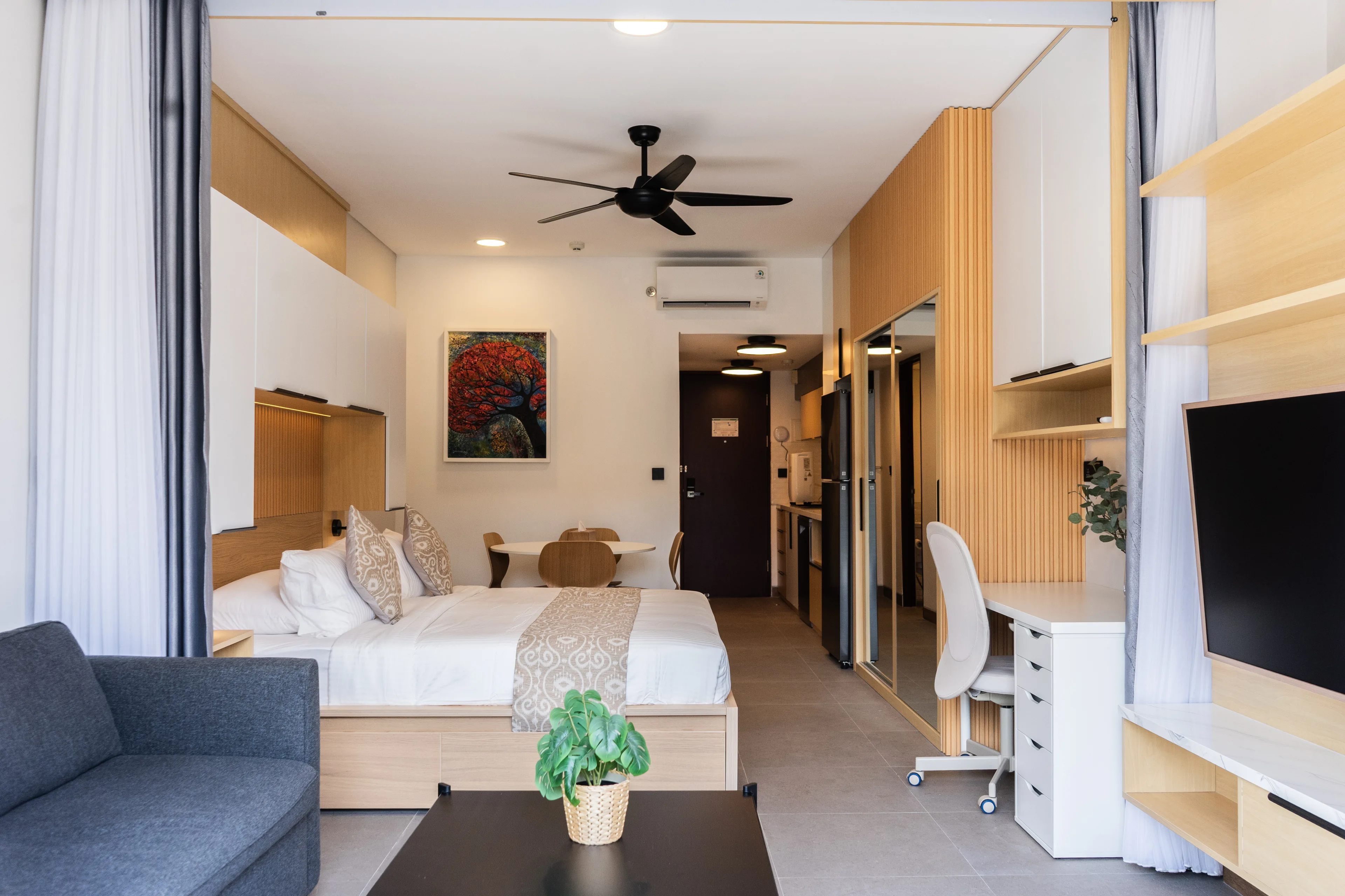 A de Lagoon residence in one frame — bed, sofa, study desk and the curtains to the balcony