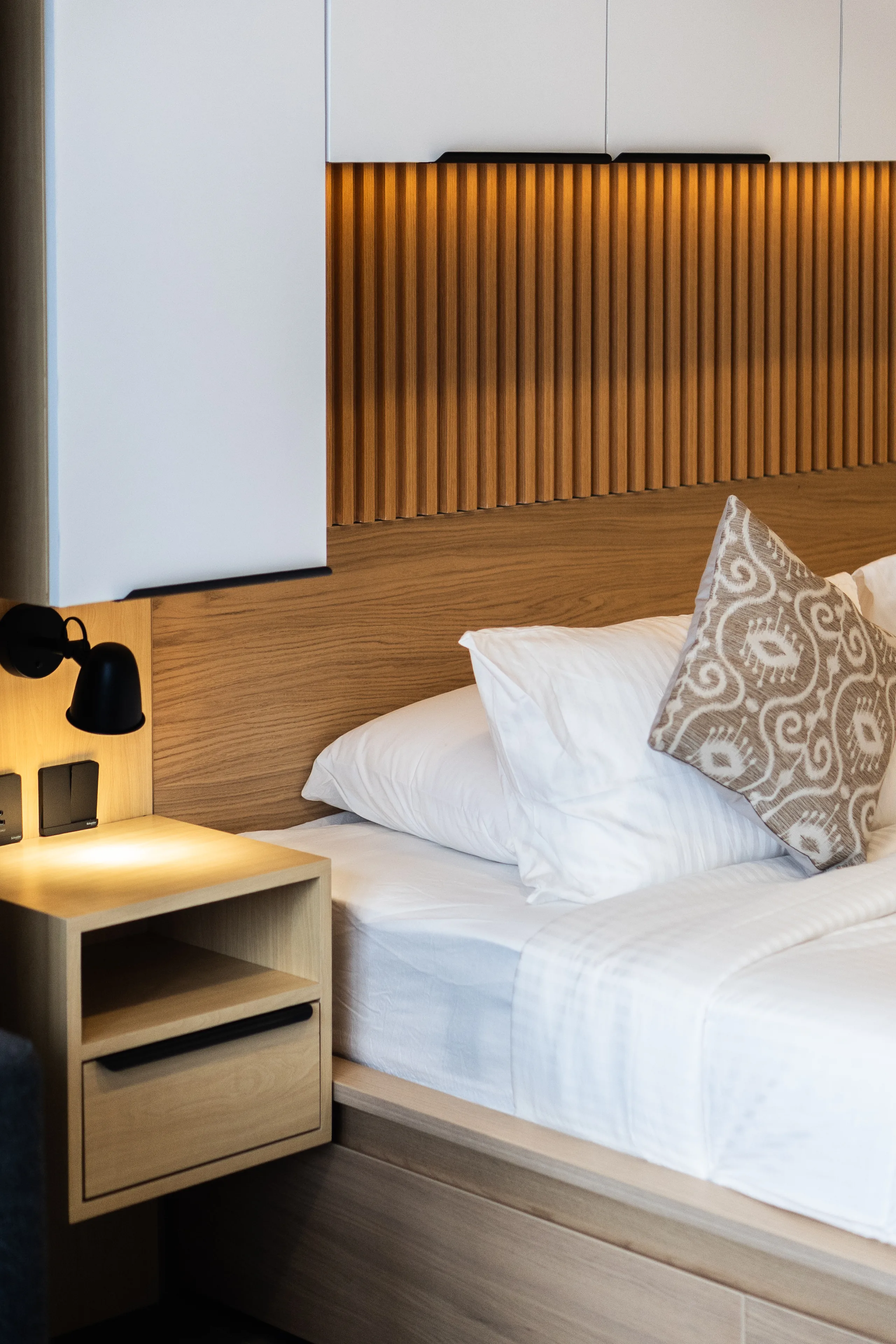 Bed and timber-slatted headboard in a renovated de Lagoon residence, with its reading light