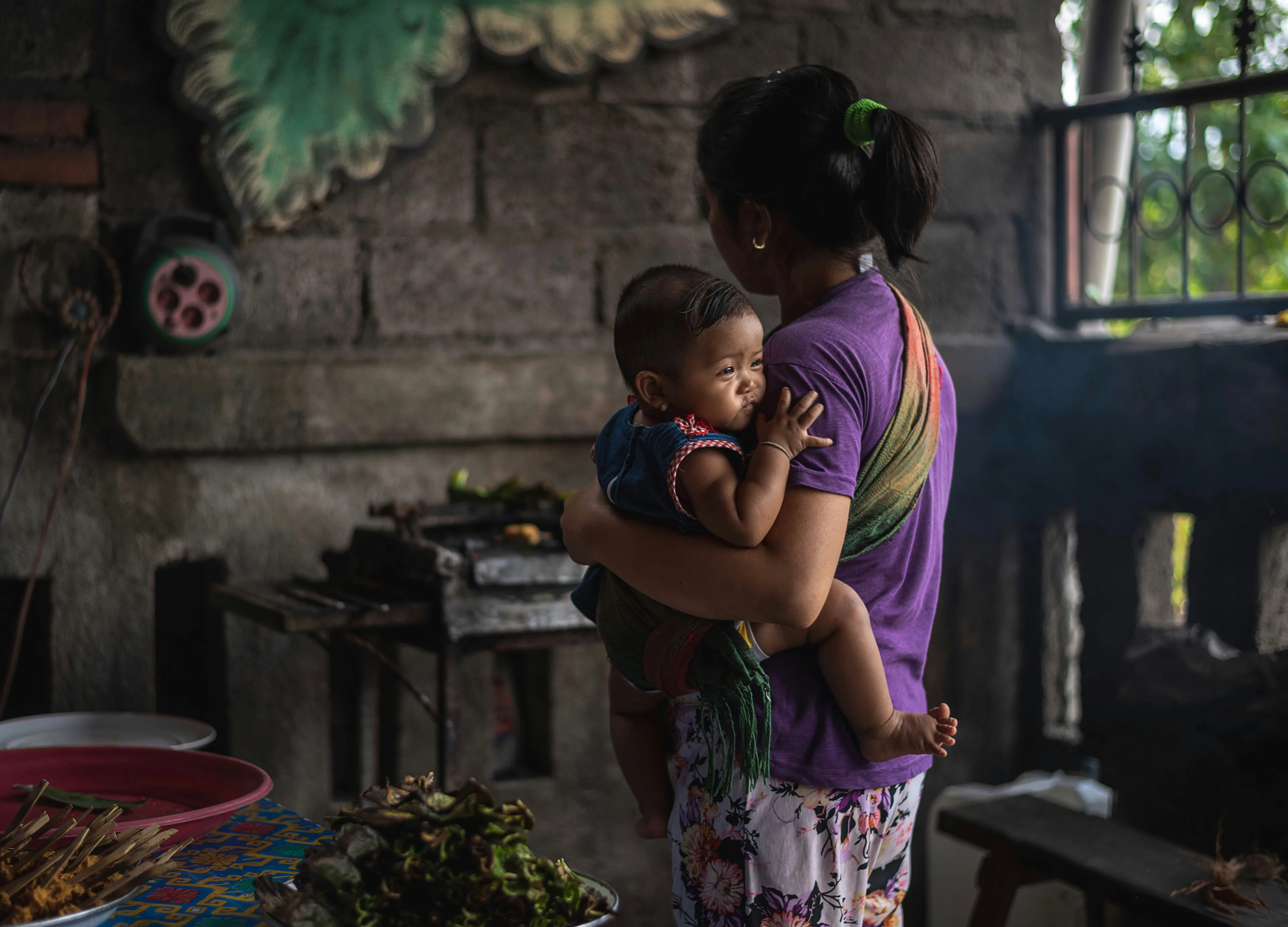 A Balinese mother holding her child at home — the families Yayasan Belarasa Bali Indonesia supports