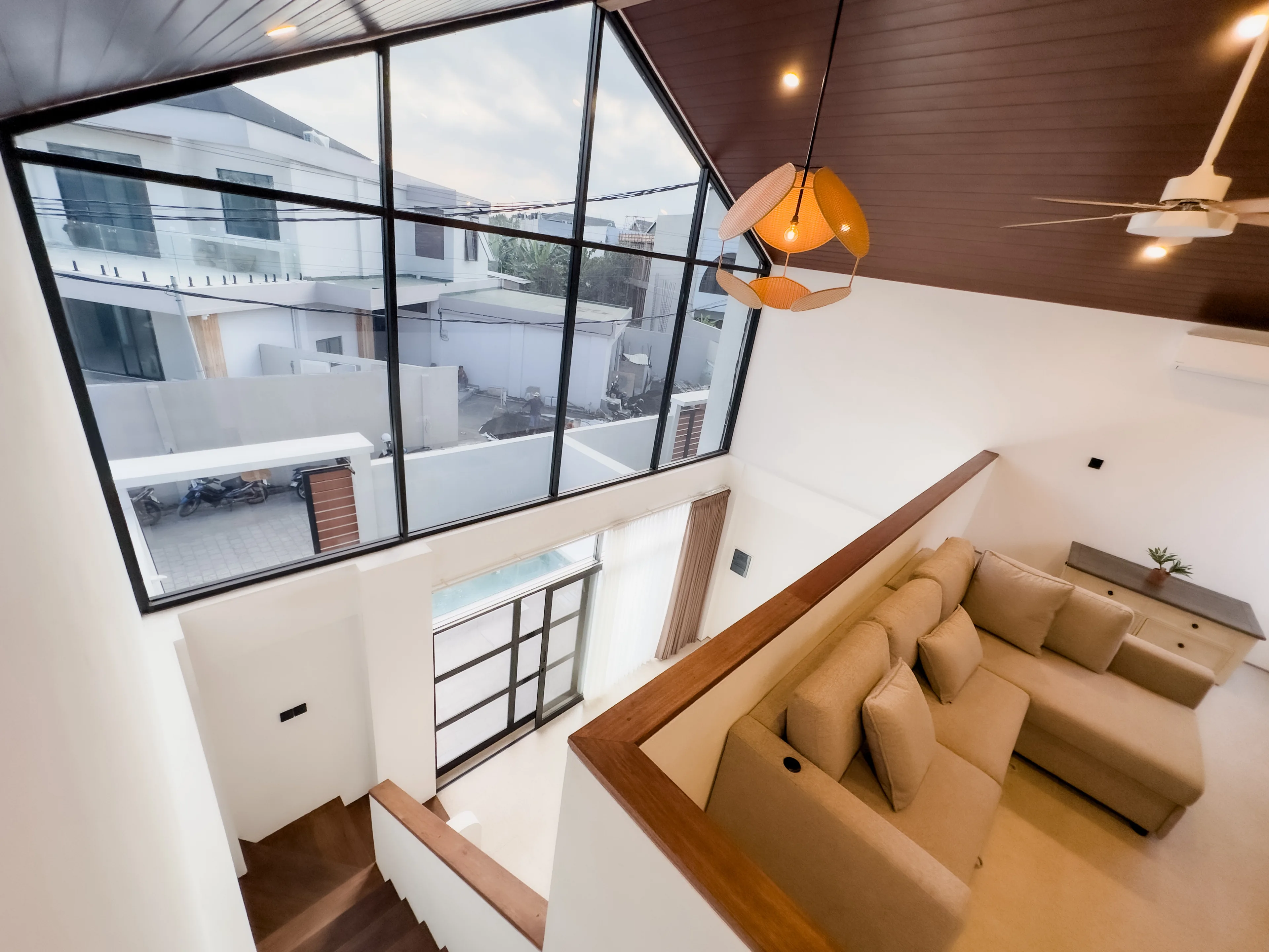 Looking down from the mezzanine over the living area and its gable glazing in a delivered villa