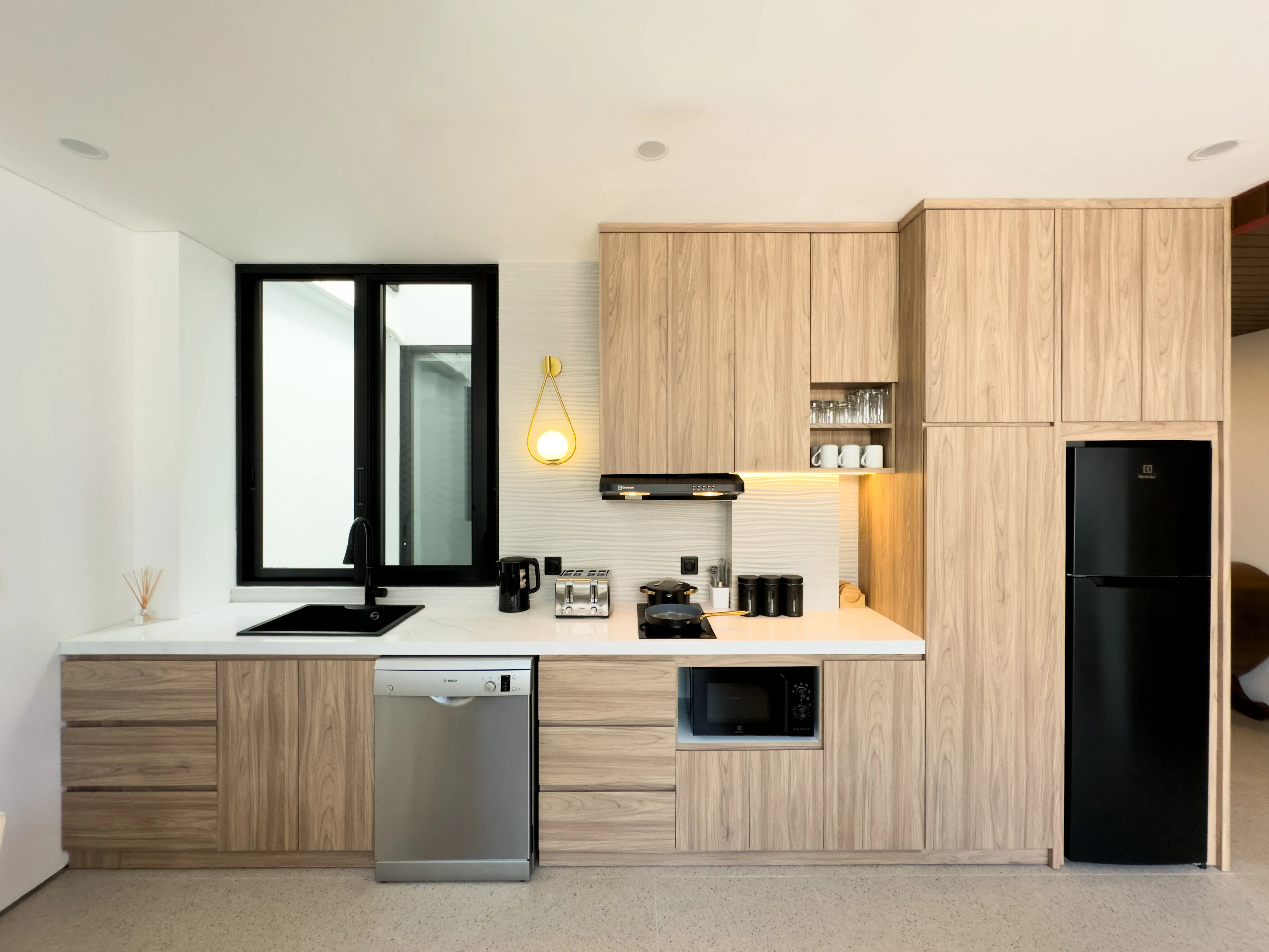 Kitchen in a delivered villa, with timber joinery, an integrated dishwasher and a full-height fridge